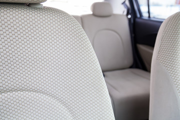 Upholstery of the seats of the passenger compartment of a luxury car with beige textile material in a workshop for hauling vehicles with a seam of thread.