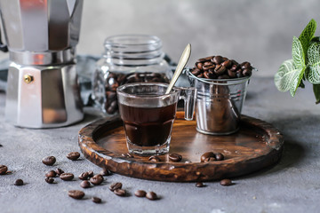 Photo of coffee in glass and beans. Spoon. Coffee pot. Glass cup. On rusty table. Gray background. Woodeen