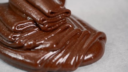 Putting chocolate dough on a baking sheet covered with parchment for baking cake