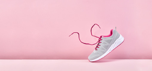 Pair of fashion stylish sneakers with flying laces, Running sports shoes on pink background