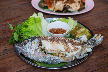 Grilled Fish with thai sauce and vegatable on wood table