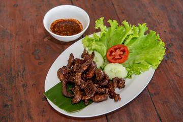 Fried Sun-dried Beef with sauce on the wood table
