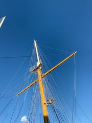 Wooden ship masts in the blue sky background