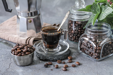 Photo of coffee in glass and beans. Spoon. Coffee pot. Glass cup. On rusty table. Gray background. Woodeen