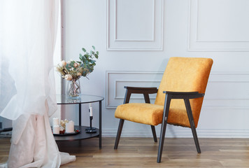 Interior of contemporary living room with a orange armchair glass table and plaster frame on wall