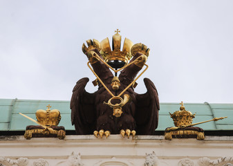 Wooden biped eagle with touches of gold on top of an Austrian building.