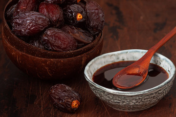Natural date syrup in a bowl with whole dates in the background