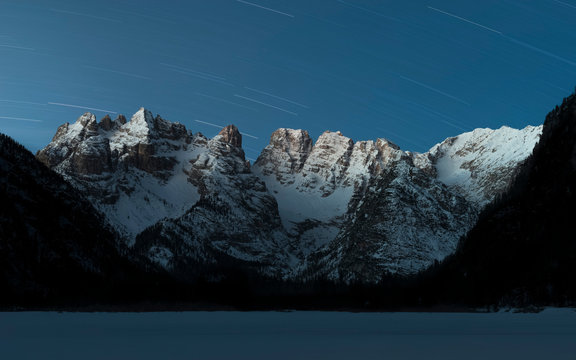 First lights on Monte Cristallo mountain range during a winter dawn with stars in the sky, Landro lake, South Tyrol, dolomites, Italy, Europe