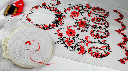 Towel towel with a traditional Ukrainian national embroidery in the manufacturing process and a hoop with a needle and thread on a white background.