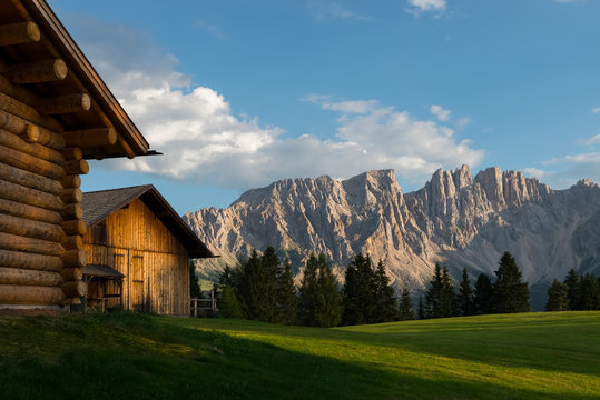 The Latemar framed by a blu sky, a green meadow and a chalet made of wood, Carezza, dolomites, Trentino Alto Adige, Italy, Europe