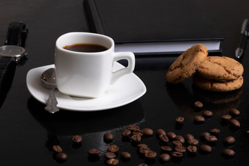 Coffee background with beans and white cup. Dark atmosphere and copy space. Oatmeal cookies and notebook