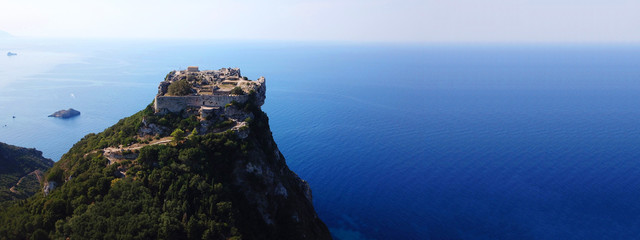 Aerial drone ultra wide view of iconic medieval fortified castle of Aggelokastro with amazing views to Paleokastritsa bay, Corfu Greece