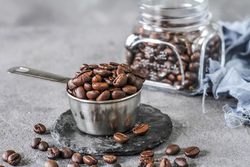 Photo of roasted coffee beans. Dark roasted. Spoon. Coffee pot. Glass cup. On rusty table. Gray background
