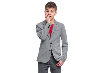 Emotional portrait of caucasian teen boy, isolated on white background. Funny child teenager looking at camera and shocked. Handsome surprised boy in gray suit.