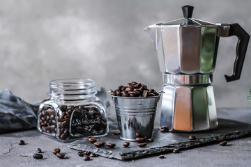 Photo of roasted coffee beans. Dark roasted. Spoon. Coffee pot. Glass cup. On rusty table. Gray...