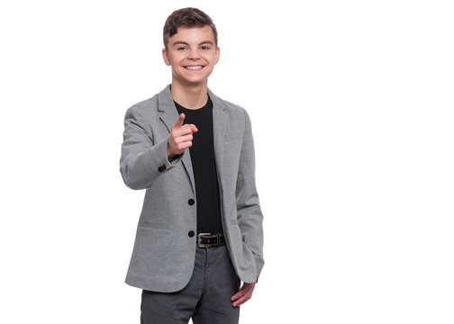 Emotional Portrait Of Handsome Caucasian Teen Boy In Suit Laughing And Pointing Finger To You. Funny Cute Smiling Child 15 Year Old Looking At Camera Choosing You, Isolated On White Background.