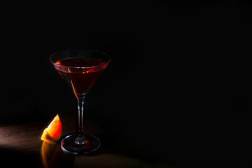 bright cocktail with red orange in a ray of light on a dark background