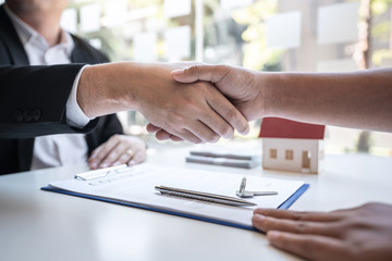 Fototapeta na wymiar Real estate agent are shaking hands after good deal and giving house, keys to customer after signing contract to buy house with approved property application form