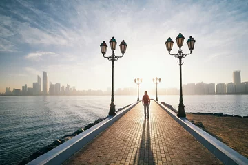 Foto op Plexiglas Man walking on sidewalk against urban skyline at sunrise © Chalabala