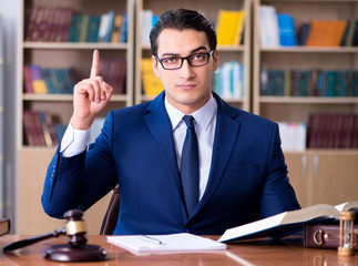 Handsome judge with gavel sitting in courtroom