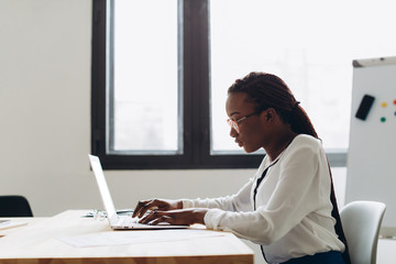 Pretty african american business woman working on laptop in office