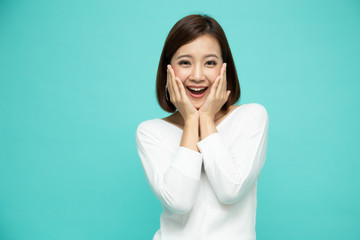 Portrait of excited screaming young asian woman standing isolated over green background, Wow and...