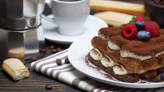 tiramisu dessert with raspberries. blueberries, cup of espresso and coffee maker on wood