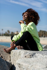 Beautiful afro american woman sitting on shore in a sunny day