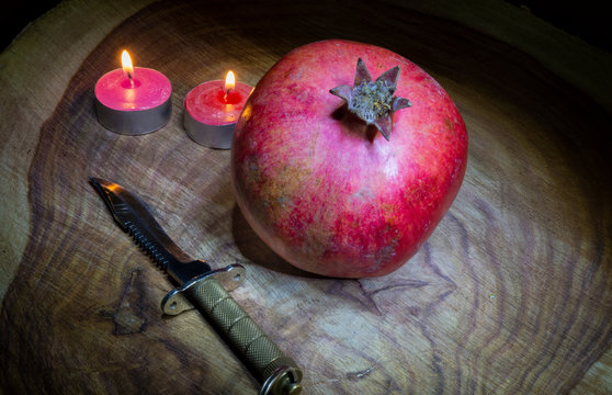 Close up photo of pomegranate, Knife and candal on wooden background