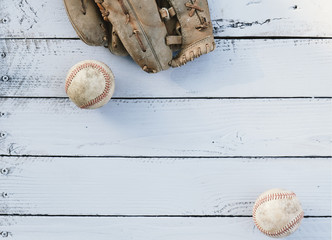 Baseball glove and balls on wood background, flat lay of sports equipment.