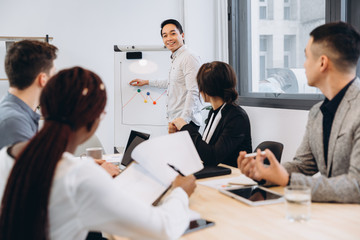Group of multicultural businesspeople listening their boss speech - asian man manager talking to his team