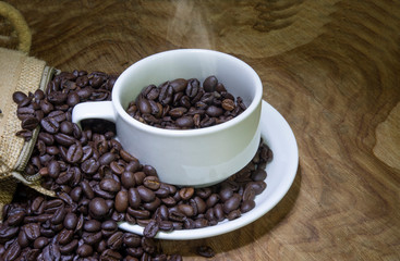 Cup full of coffee beans on wooden background with copy space