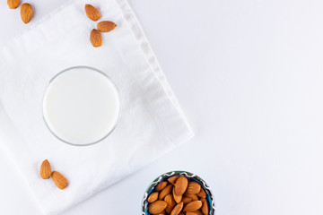 Almond milk with almond on white background. Organic almond milk in a glass for healthy breakfast. Vegan milk from almonds nuts on a white napkin. Alternative milk