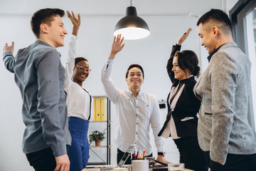 Multiracial euphoric business team people give high five at office table, happy excited diverse...