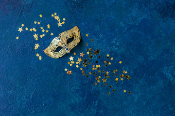 Carnival mask and gold glitter confetti. Top view, Close up on classik blue background..