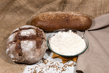 On the table is a saucer of flour and two types of bread with bran.