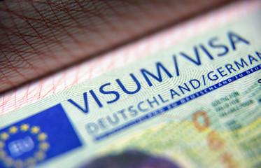 Visa stamp in passport close-up. German visitor visa at border control. Macro view of Schengen visa...
