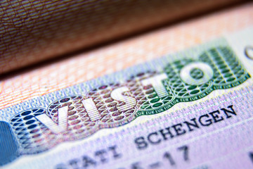 Visa stamp in passport close-up. Italian visitor visa at border control. Macro view of Schengen...