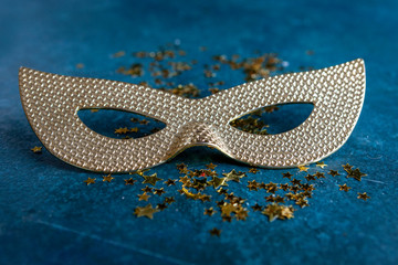 Carnival mask and gold glitter confetti. Top view, Close up on classik blue background..