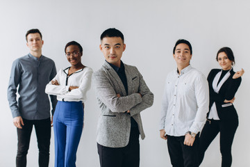 Cheerful multiracial professional business people laughing together standing in row near wall, happy diverse young employees students group, corporate staff team having fun, human resource concept