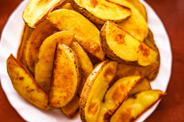 Close-Up Of Prepared Potatoes In white dish.Fried Potato Wedges on white dish a wood table.Directly Above Shot Of Fried Potatoes In Bowl.Fast food.Golden yummy Fried Potato Wedges,top view, lifestyle