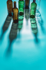 Empty alcohol bottles, hard light, glass shadows on a blue background, top view, space for text