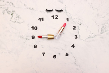 Fototapeta na wymiar Creative clock made of make up and cosmetics products with lipstick clock wise 