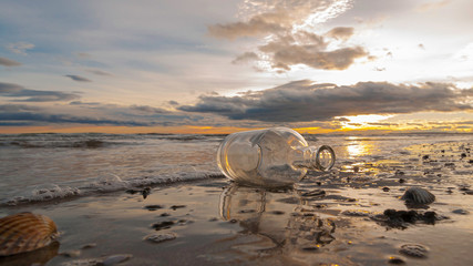 Bouteille en verre sur le sable d'une plage au coucher de soleil.