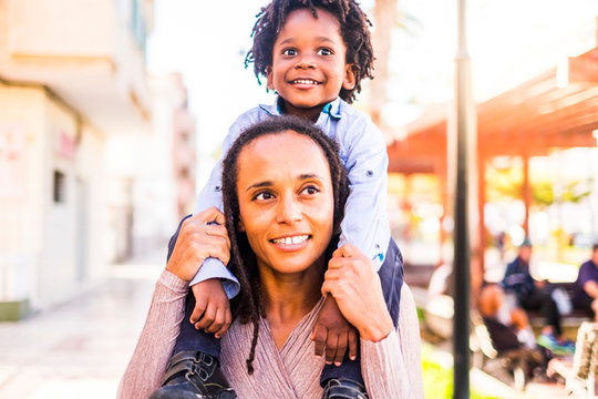 Cheerful Happy Black Race African Family Enjoying Love And Smile A Lot With Mother Carrying Little Children Son On His Shoulders In The City - Ethnici Diversity People Concept Have Fun Together