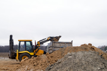 excavator pours soil into a truck body