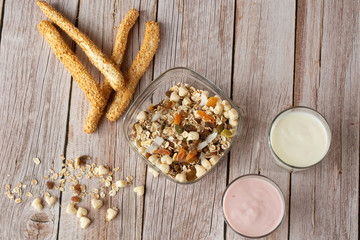 Two glasses of healthy strawberry and classic yogurt with oats on wooden table. healthy breakfast. close up with copy space. homemade fresh yogurts with cereals , two glasses of dairy product.