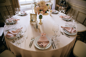 Catering service. Table set for dinner. Dinnerware with plates on table with flowers  and candles