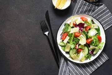 Green salad with tomatoes and fried bread on a dark concrete background. Top view with place for text.