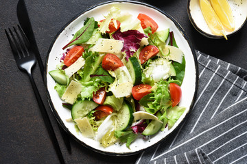 Green salad with tomatoes and fried bread on a dark concrete background. Top view with place for text.